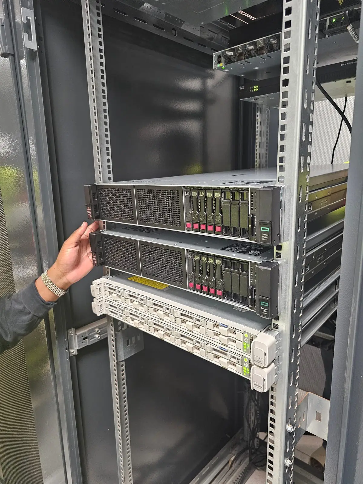 Deux serveurs en cours de montage dans une baie informatique ; une main guide l’un d’eux sur ses rails.